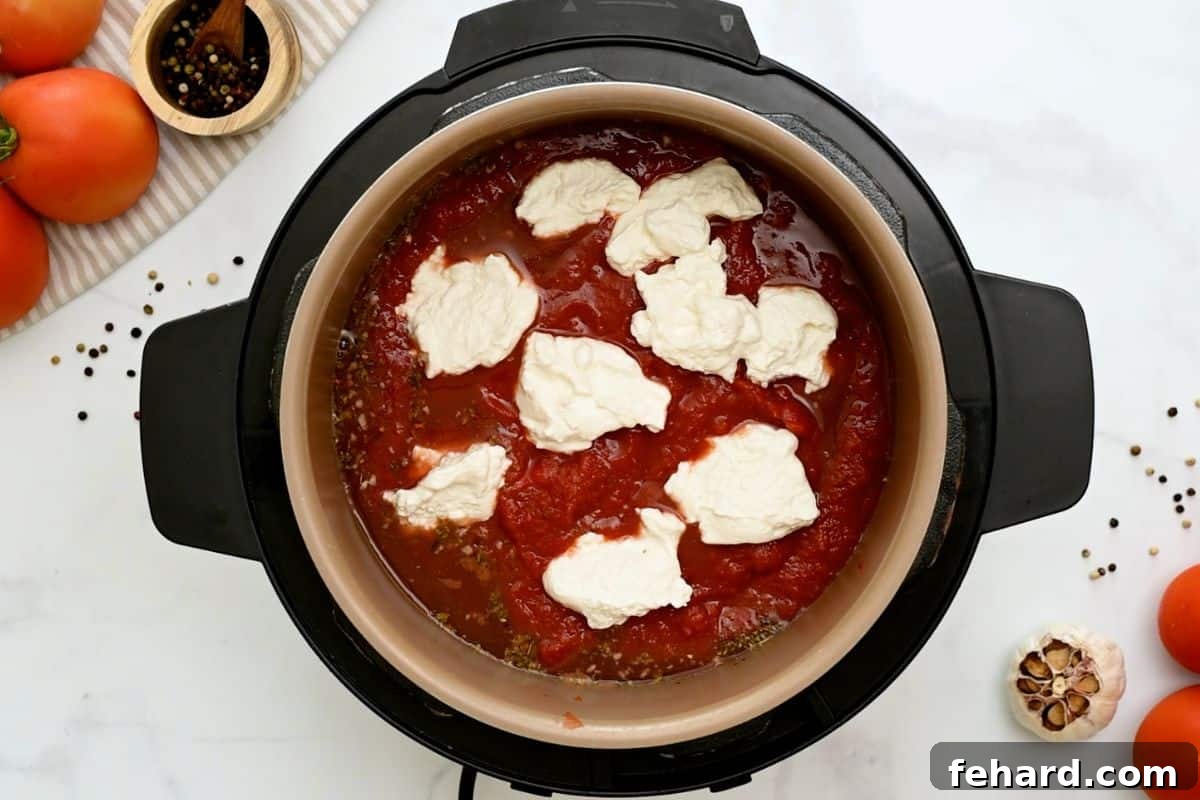 Stock, wine, seasonings, and ziti noodles layered inside Instant Pot, topped with tomato sauce and generous dollops of ricotta cheese.