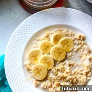 Bowl of Instant Pot Oatmeal topped with sliced banana and maple syrup.