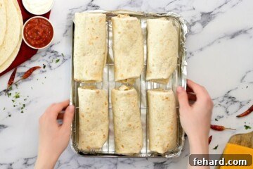 Assembled bean burritos on a baking sheet fitted with a wire rack, ready for baking.
