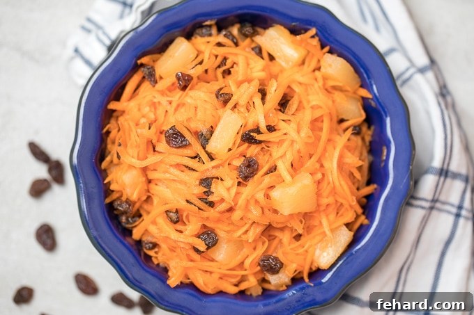 A beautifully presented Carrot and Raisin Salad with pineapple in a vibrant blue bowl, perfectly chilled and ready to serve.