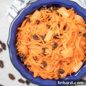 Carrot Raisin Salad with pineapple in a blue serving bowl, visually appealing and ready to be served.
