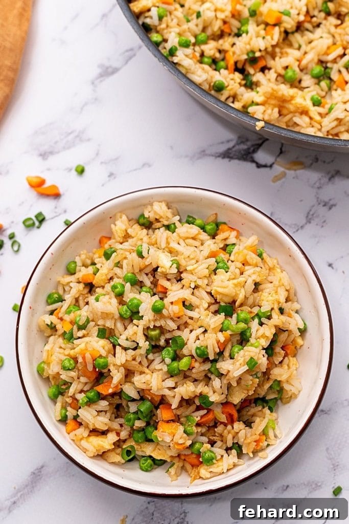 Delicious Homemade Veggie Fried Rice in a bowl, with a skillet full of fried rice in the background