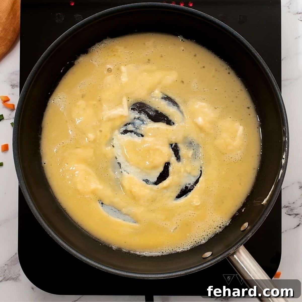 Scrambled eggs cooking in a saute pan, ready to be added to fried rice.