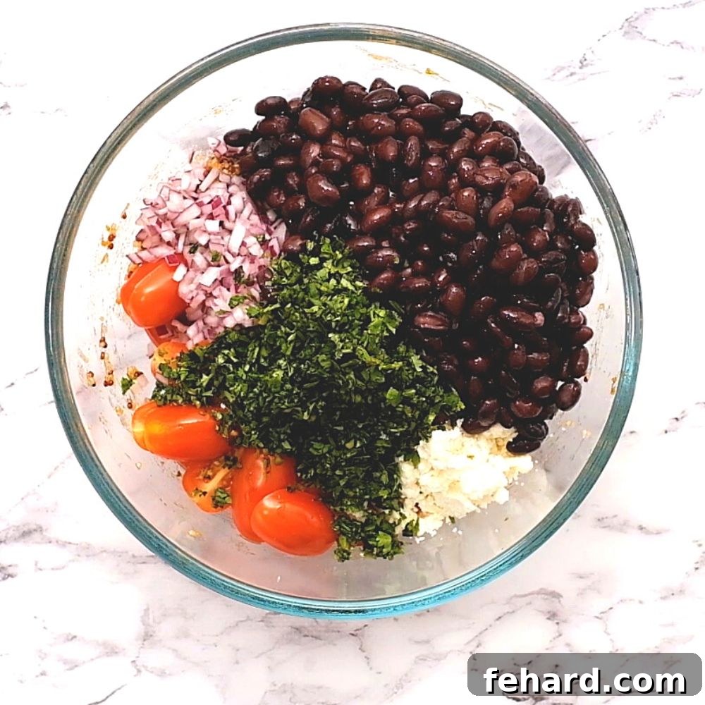 Quinoa Salad with Beans and Vegetables Ingredients for Mexican quinoa salad in a large mixing bowl, showing the colorful blend of beans, tomatoes, corn, and quinoa.