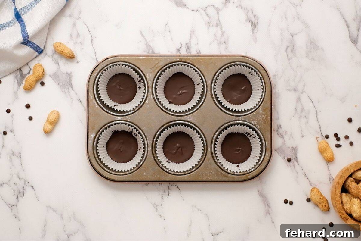 Melted chocolate that has hardened in muffin tin liners to form the base of a Reese's peanut butter cup.