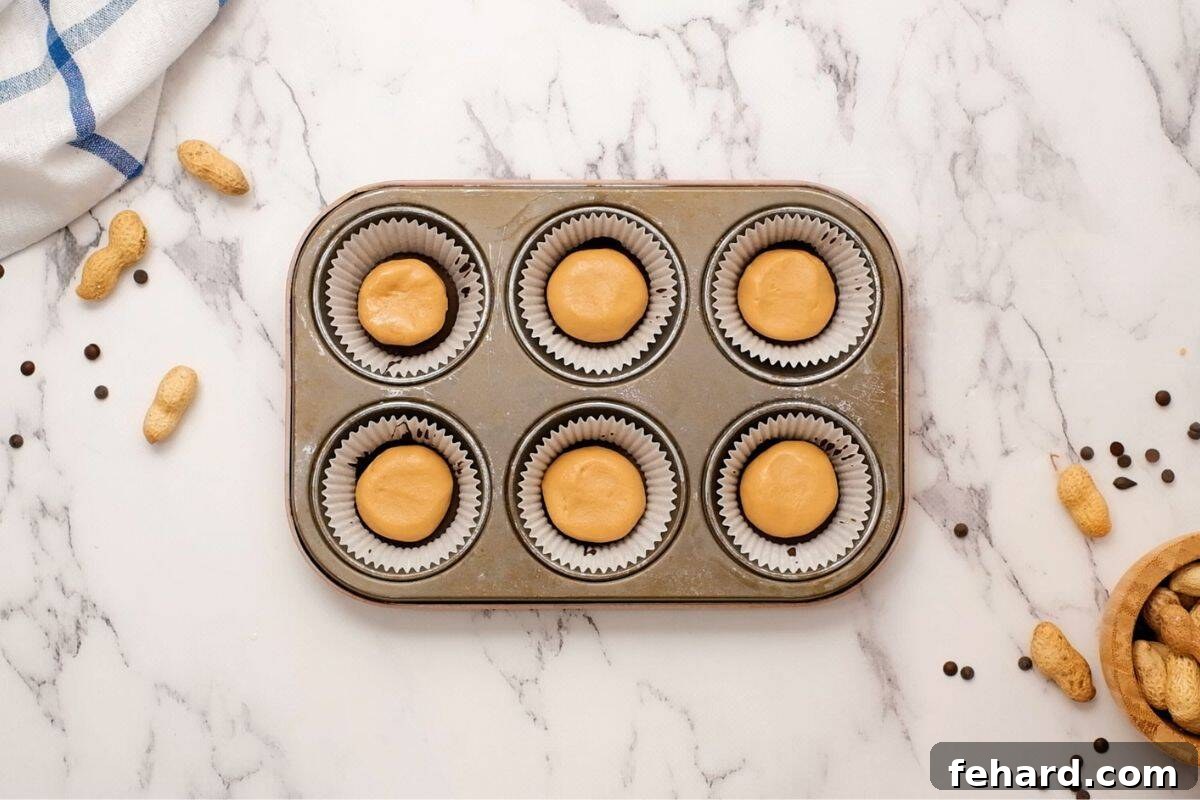 Neatly shaped peanut butter discs placed on top of chocolate base layer to form the central layer of the peanut butter cups.