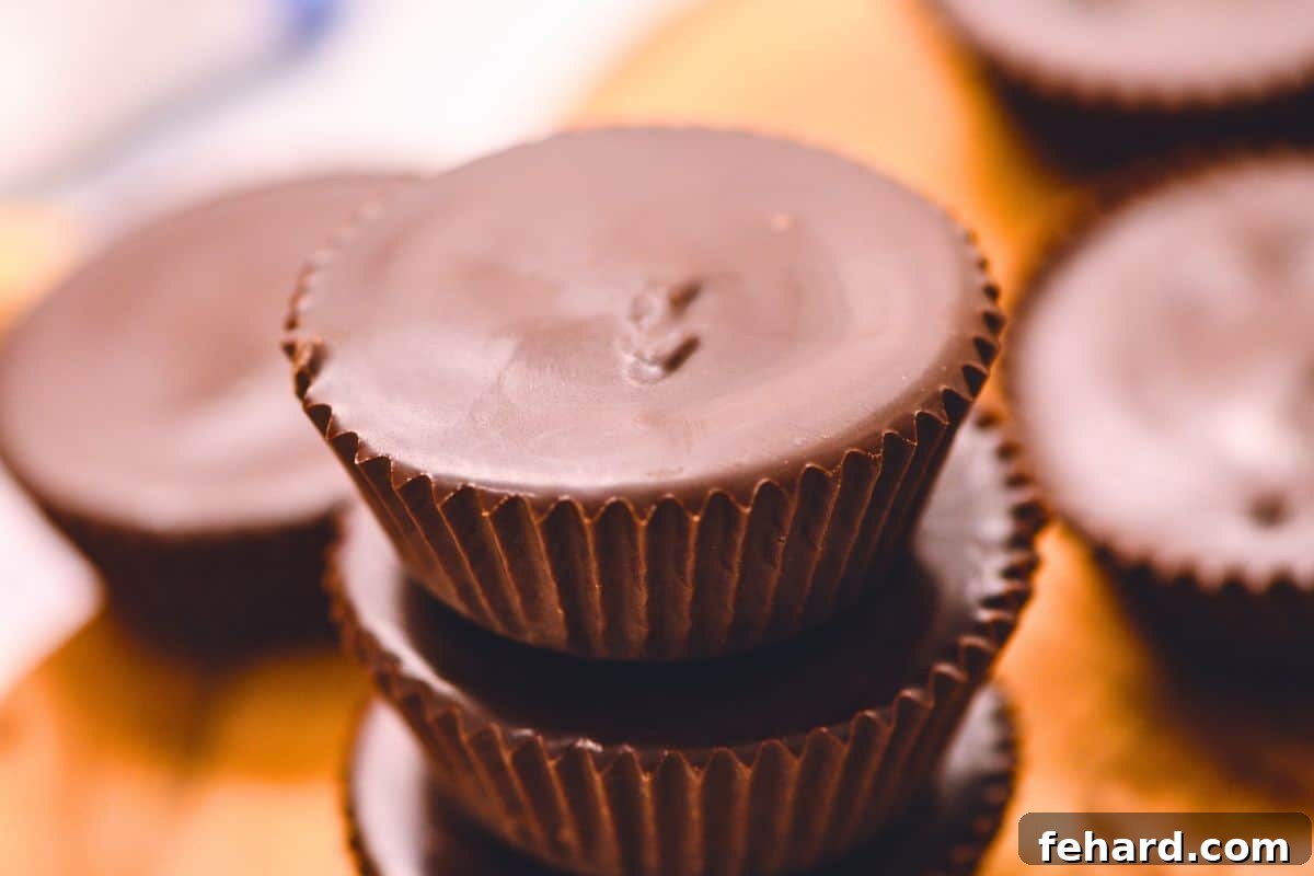 Homemade peanut butter cups stacked on top of each other on a wooden cutting board, ready for enjoyment.