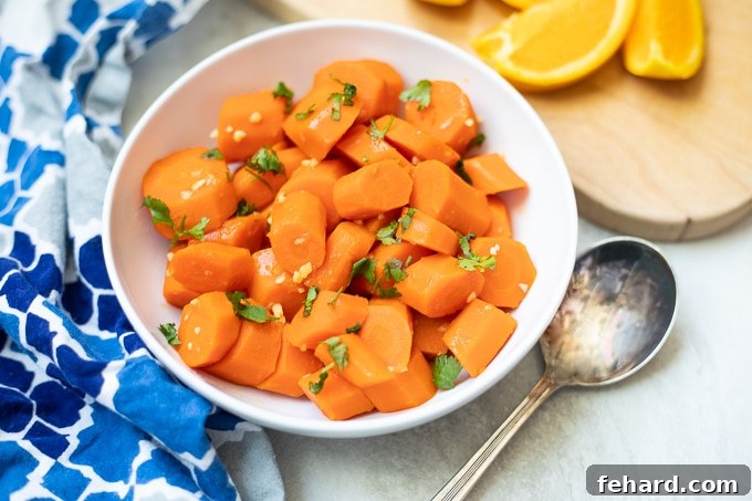 Quick & Sweet Glazed Carrots 7 A serving bowl of finished glazed carrots, garnished with fresh herbs, alongside fresh orange slices.