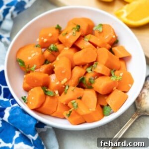Bowl of Maple Syrup Glazed Carrots with fresh oranges in background.