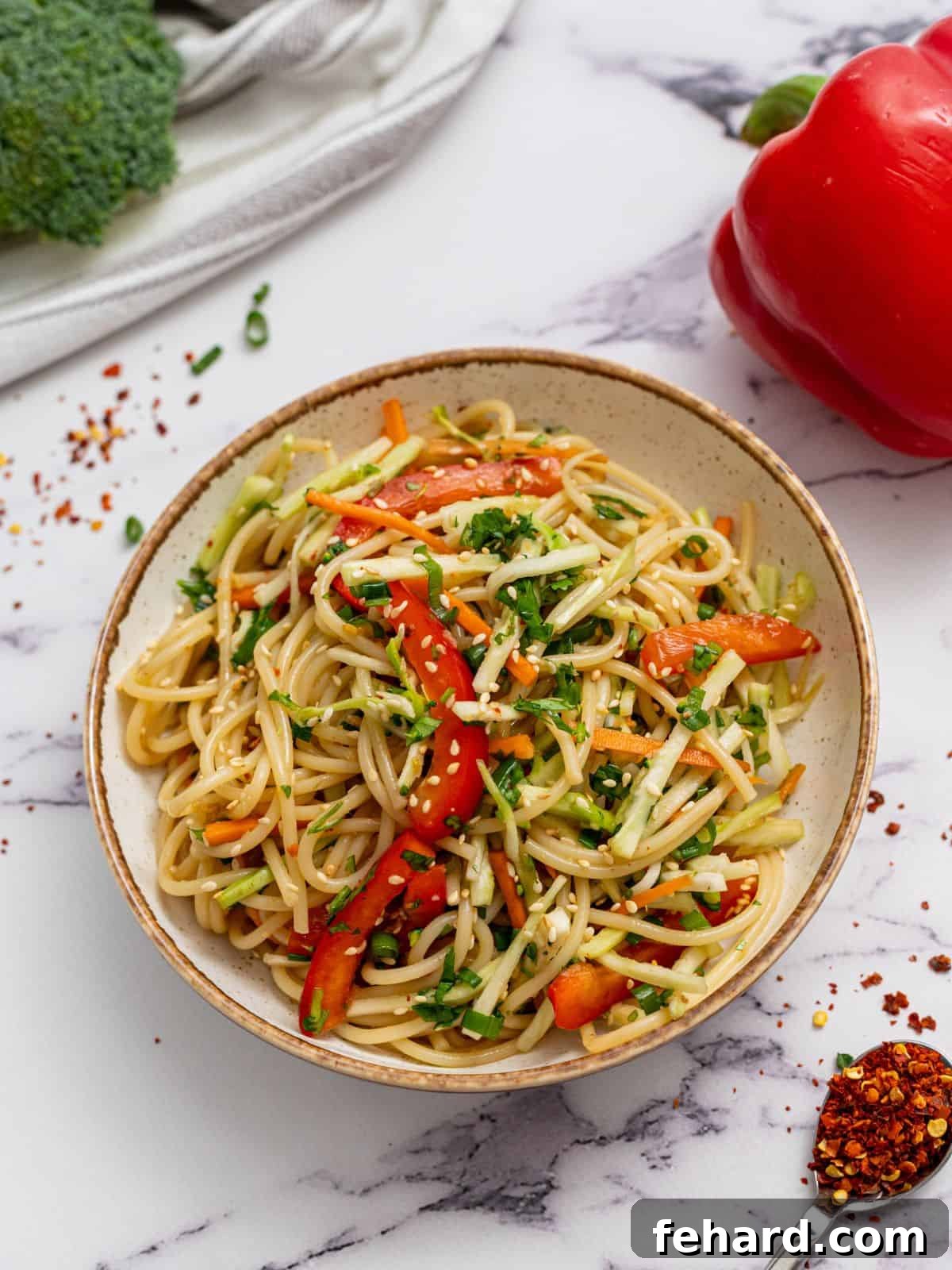Cold Asian Noodle Salad Recipe A beautifully presented Asian noodle salad in an elegant pottery bowl, garnished with sesame seeds and fresh herbs.