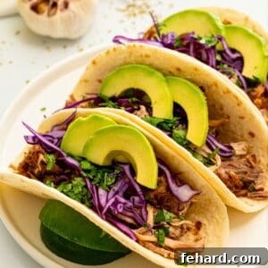 Instant Pot Carnitas meat on flour tortillas topped with cabbage and sliced avocado.