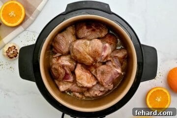 Seared pork roast inside inner pot topped with orange juice, beer and seasonings to make Instant Pot Carnitas.