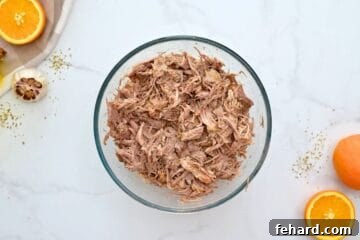 Pressure cooked pork taco meat shredded in mixing bowl.