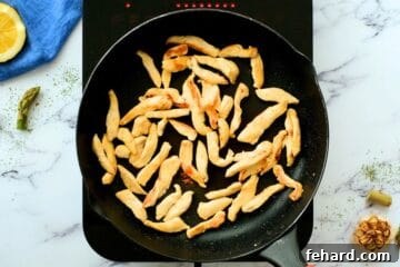 Thin slices of chicken in a saute pan in skillet.