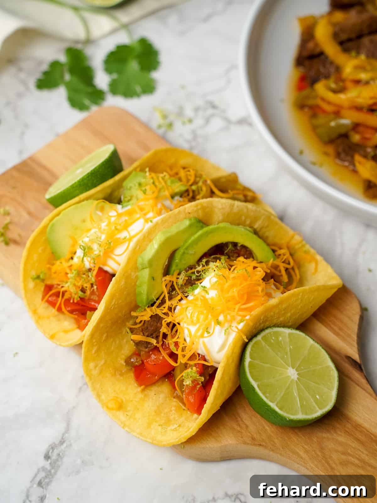 Steak Fajita mixture served on corn tortillas topped with cheese and sour cream. A perfectly cooked and vibrant Instant Pot Steak Fajita dish.