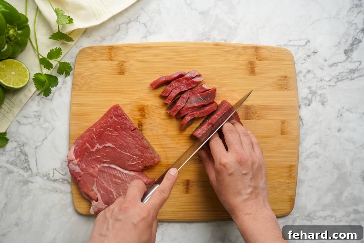 Sirloin Steak thinly sliced on cutting board. Perfectly cut strips of beef ready for seasoning.