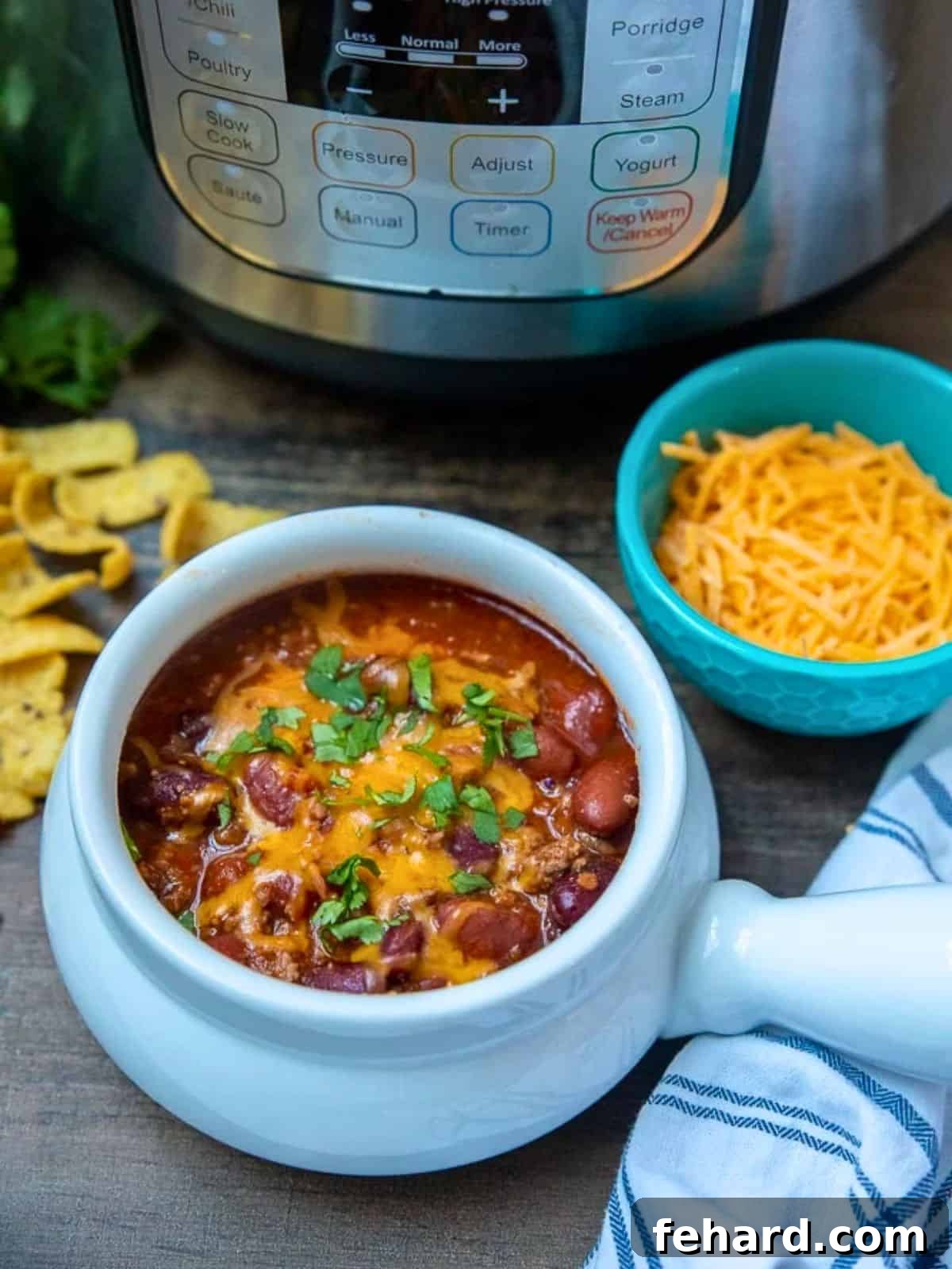 Instant Pot Chili: The Ultimate Beef and Bean Recipe Instant Pot Classic Beef Chili in white bowl next to Instant Pot with corn chips and cilantro on the side.