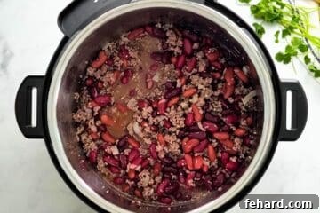 Sauteed beef with beer, beef stock, and kidney beans mixed together inside Instant Pot.