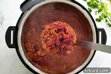 Scoop of Beef and Bean Instant Pot Chili being ladled out of Instant Pot.