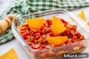 Glass Dish with creamy taco dip, garnished and ready to serve.
