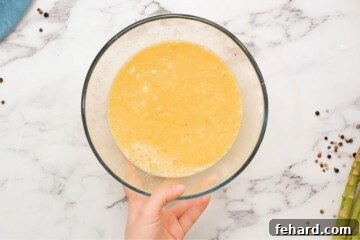 Whisked eggs with cheese and cream in a bowl.