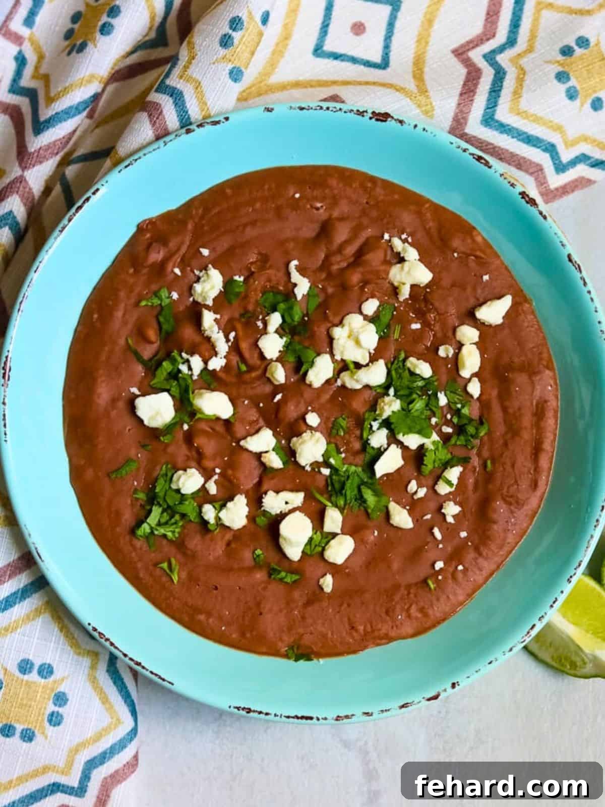 Homemade Instant Pot refried beans in a blue serving bowl topped with fresh cilantro, ready to serve.