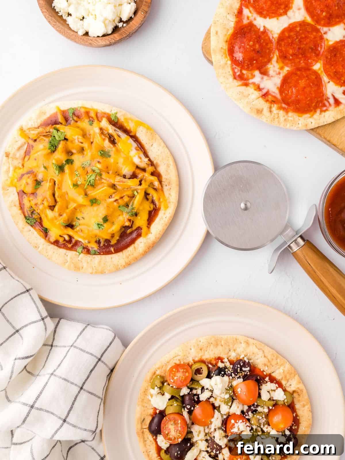 A variety of assembled and baked pita pizzas on white plates next to pizza cutter and fresh parsley, showcasing different topping combinations.
