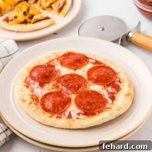 Pepperoni Pita Pizza on plate with other varieties of pita bread pizza in background.