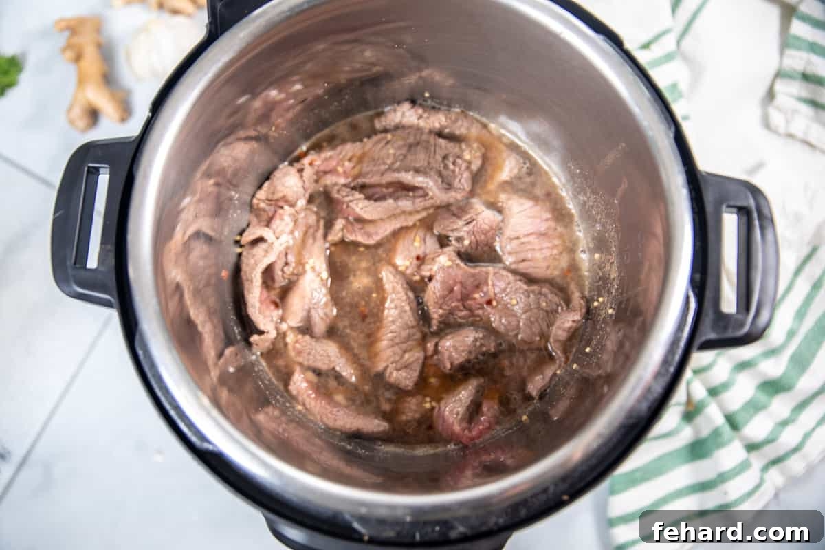 Seared beef with the freshly poured Mongolian sauce in the inner pot of an Instant Pot.