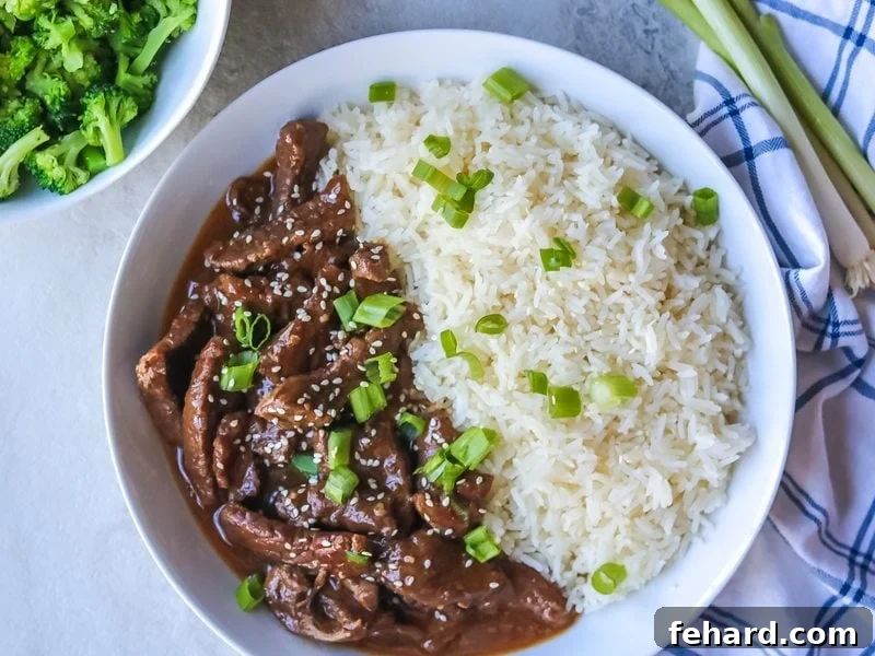 Pressure Cooker Mongolian beef in a white bowl, garnished with green onions.