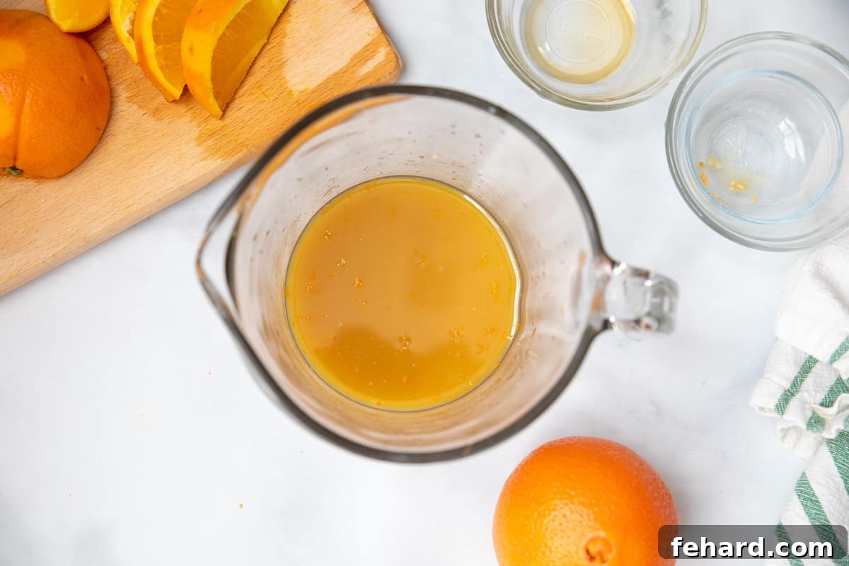 Ingredients for Orange Chicken sauce mixed together in a glass measuring cup. 