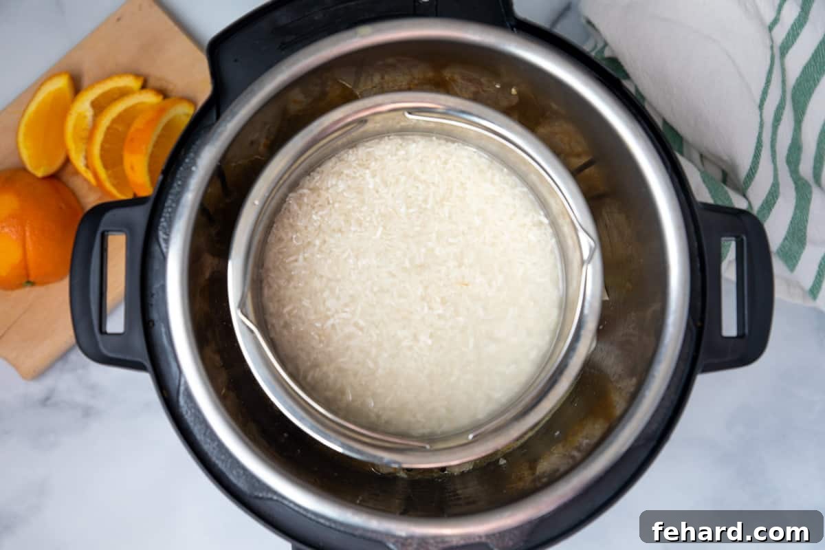 Rice in stainless steel bowl over orange chicken in instant pot.