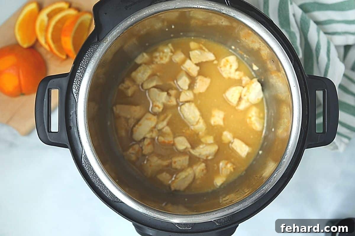 Chicken inside inner pot with orange sauce. 