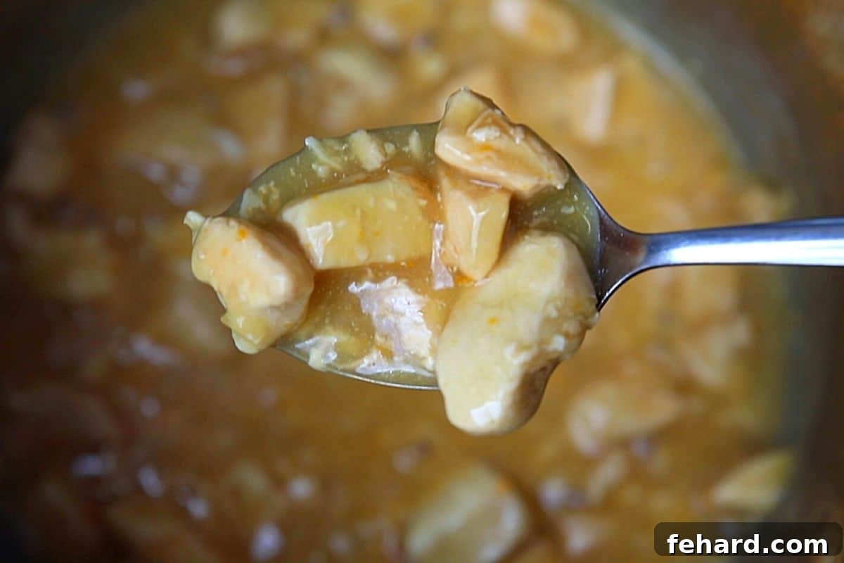 Spoon dishing out orange chicken out of instant pot. 