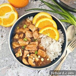 Instant Pot Orange Chicken served with rice on the side and the Instant Pot, and fresh oranges in the background.