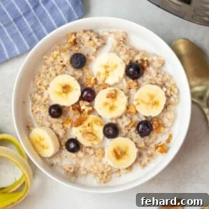 Bowl of Instant Pot Steel Cut Oats topped with sliced banana, chopped nuts, and blueberries.