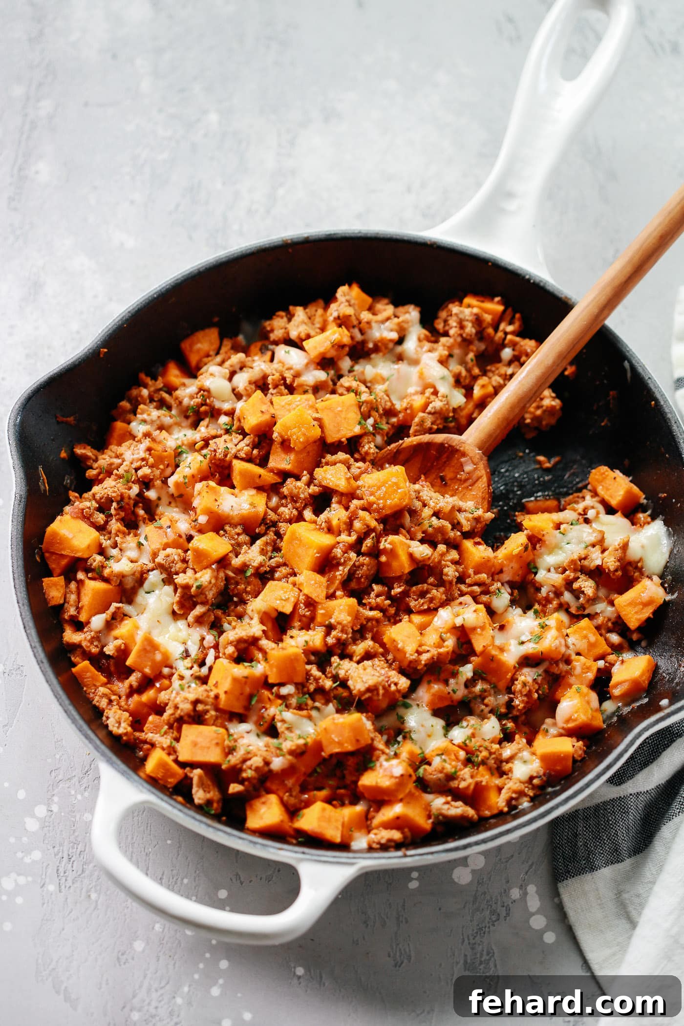 Turkey & Sweet Potato Hash 4 Overhead view of a white skillet filled with a rustic blend of ground turkey, perfectly cooked sweet potato cubes, and colorful bell peppers.