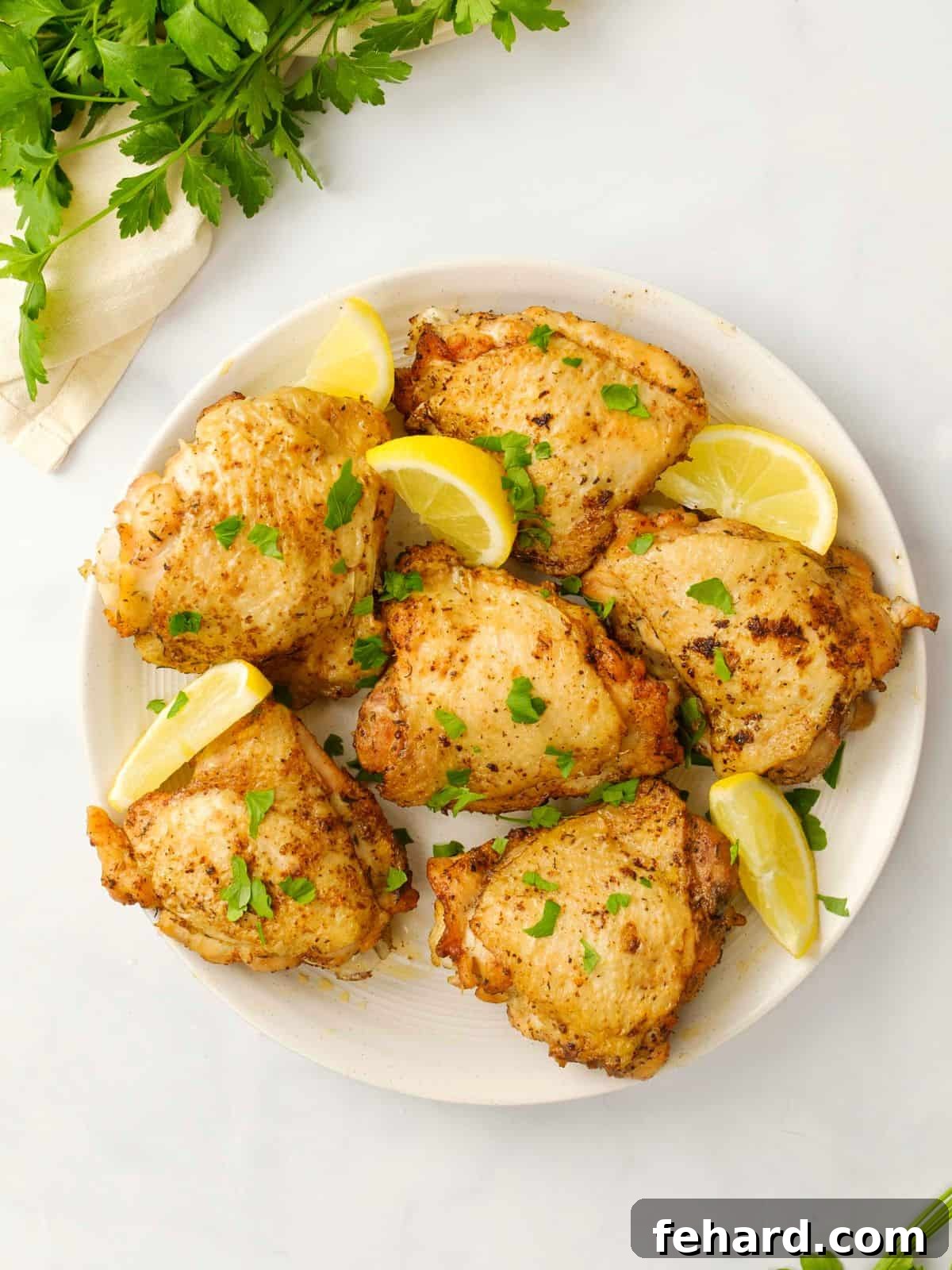 Perfectly cooked Instant Pot Chicken Thighs garnished with fresh lemon wedges and vibrant parsley, elegantly arranged on a serving plate.