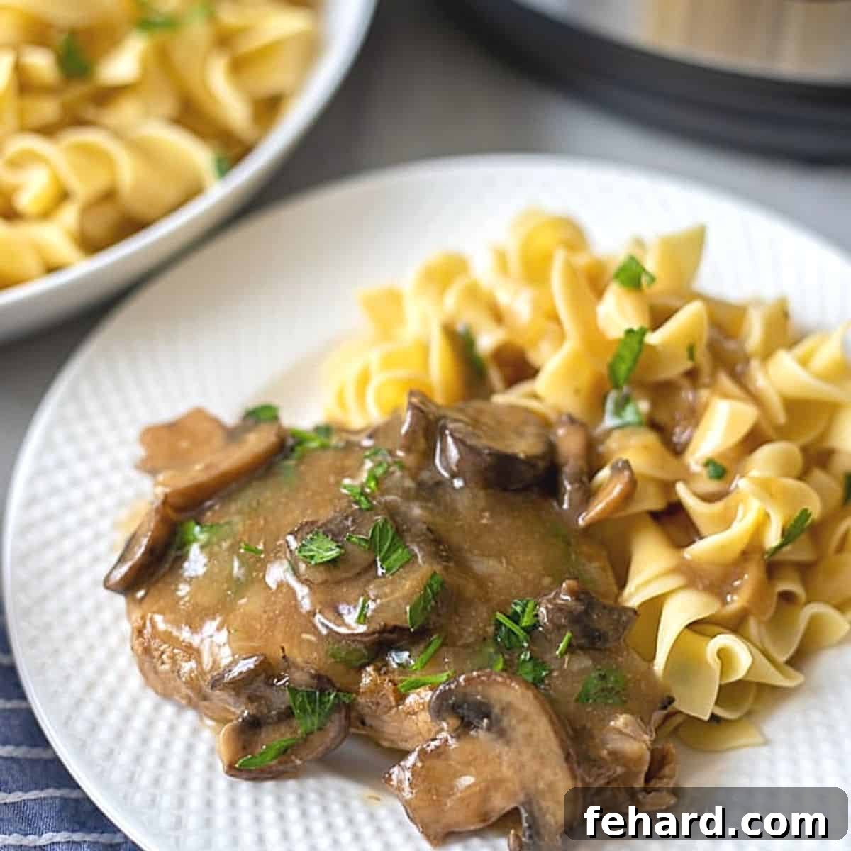 Thickening Sauces in Instant Pot Post-Pressure A savory pork chop with creamy mushroom gravy and noodles served on a white plate.
