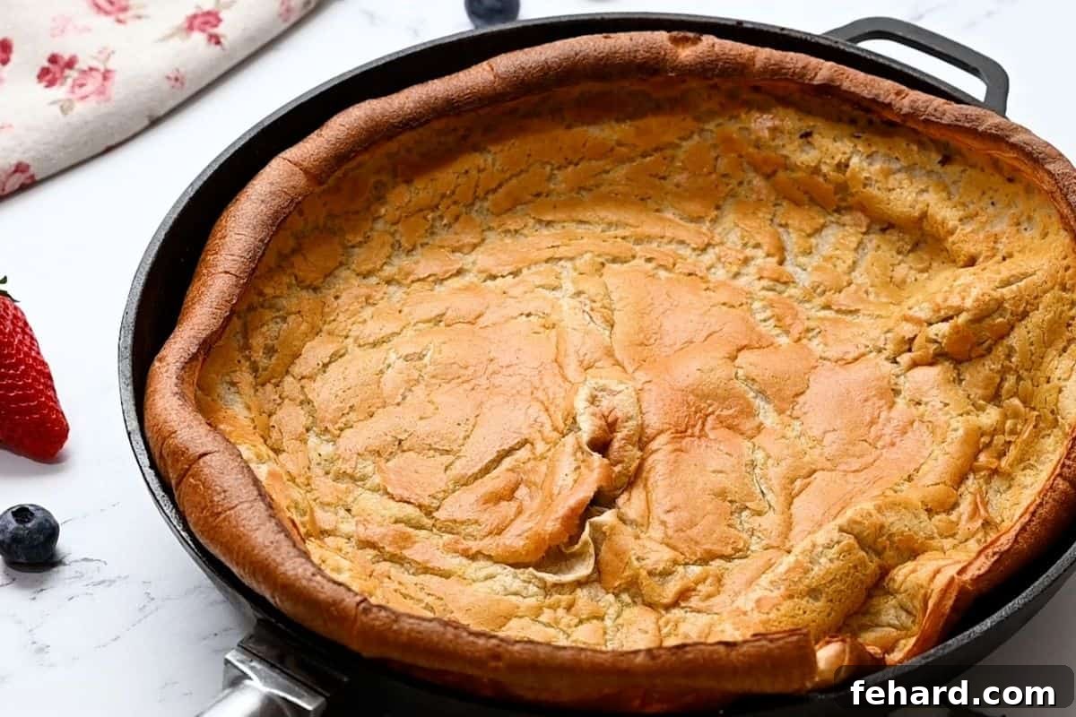 A freshly baked German Pancake, spectacularly puffed and golden brown, still in its cast iron skillet straight from the oven.