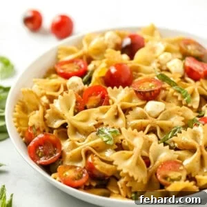 Close up of bowl of pasta salad with tomatoes and basil.