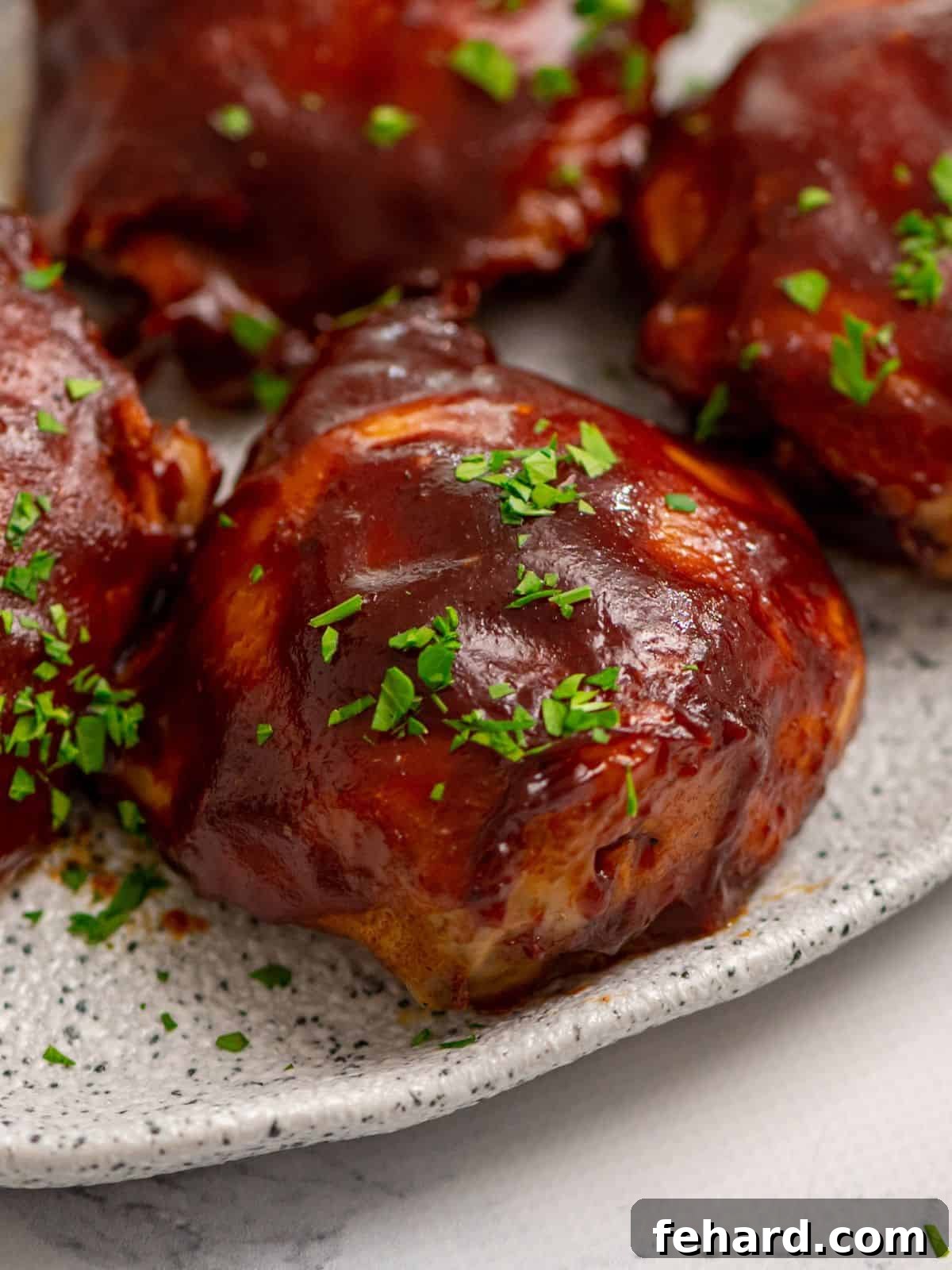 Crockpot BBQ Chicken Thighs: Your New Favorite Dinner Close up of perfectly cooked BBQ Chicken Thighs on a white platter, glistening with sauce.