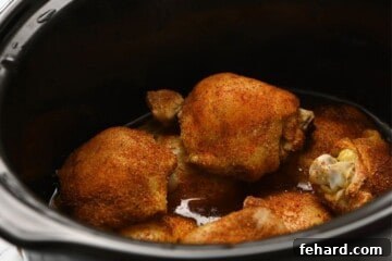 Cooked seasoned chicken thighs in the slow cooker.