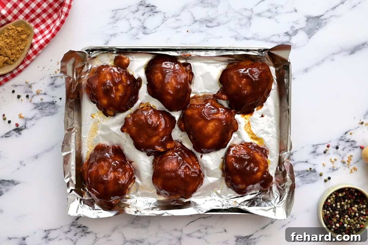 Slow Cooker Barbecue Chicken: Broiling for Perfect Glaze Crockpot Chicken Thighs on a sheet pan, generously brushed with BBQ Sauce, ready for broiling.