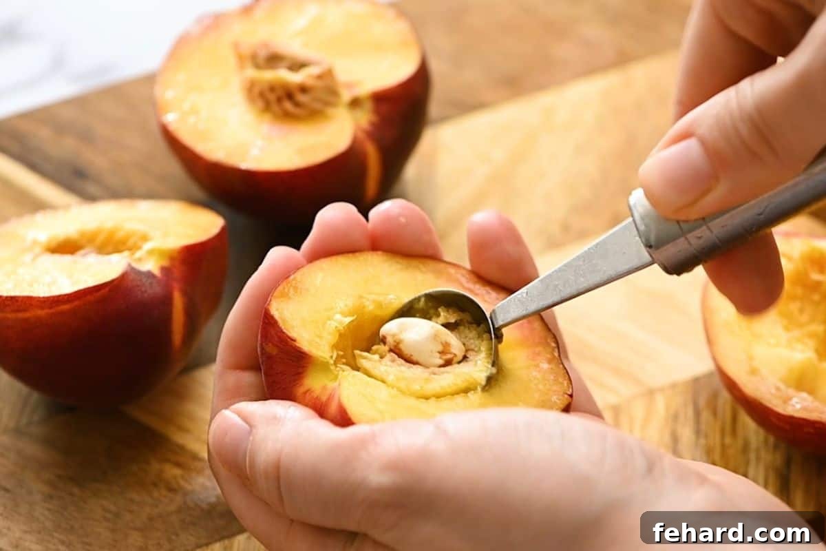 Grill Peaches: Clean Pit Removal Technique A melon baller demonstrating how to efficiently remove the pit from a peach half, showcasing a clean cavity.