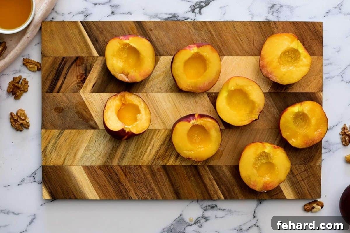 Easy Grilled Peaches: Essential Oiling Step Sliced peaches on a wooden cutting board, with a pastry brush applying a light layer of oil to the cut surface.