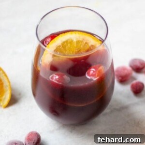 Glass of Mulled Wine next to spices and oranges.