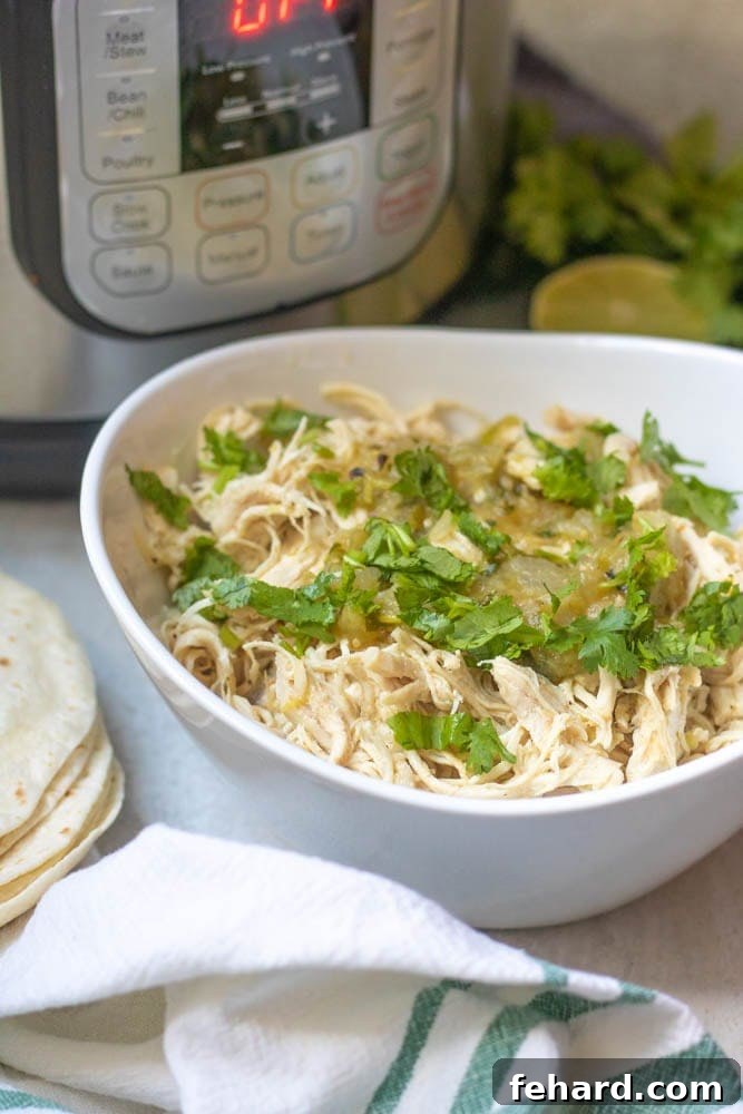 Instant Pot Salsa Verde Chicken Instant Pot Shredded Mexican Chicken in a white bowl topped with fresh cilantro, next to the Instant Pot.