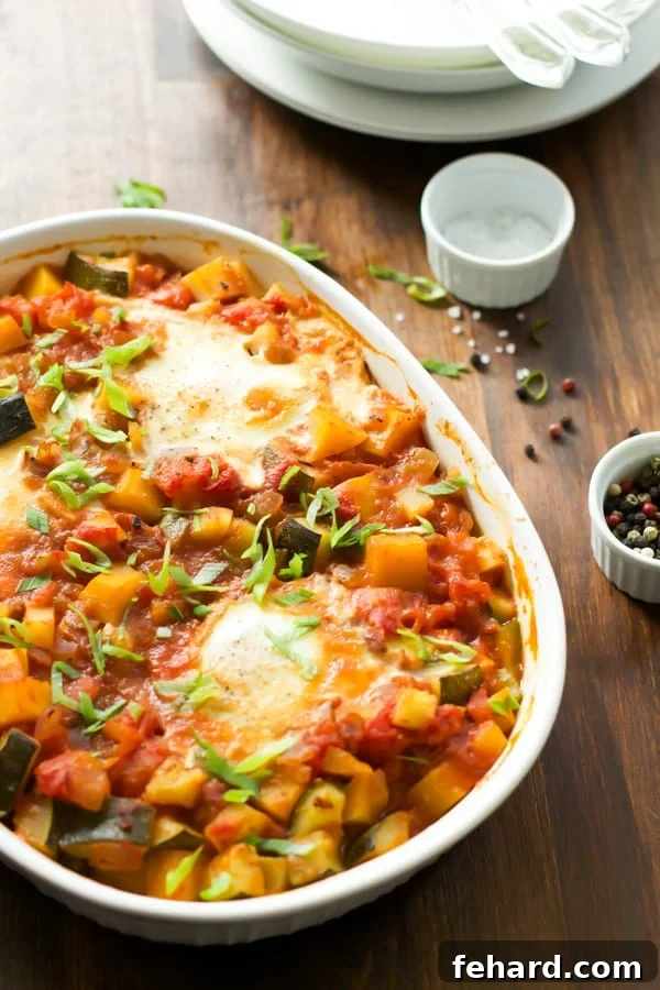 A beautifully presented white baking dish filled with perfectly baked eggs nestled among a vibrant array of mixed vegetables, garnished with fresh herbs, ready to be served.