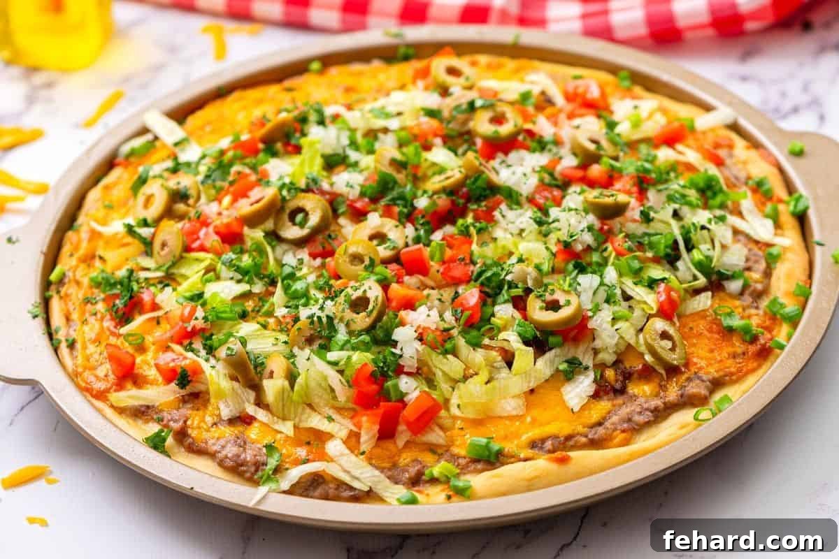 Copycat Taco Pizza garnished with fresh toppings A whole Taco Pizza beautifully adorned with an array of fresh, vibrant toppings including crisp shredded lettuce, chopped cilantro, juicy diced tomatoes, and savory black olives, now ready to be served.